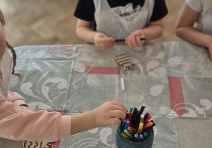 Dzieci kolorują mazakami swoje sylwety jajka wycięte zw sklejki.