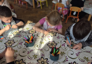 Dzieci kolorują mazakami swoje sylwety jajka wycięte zw sklejki.