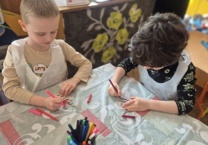 Chłopcy kolorują mazakami swoje sylwety jajka wycięte zw sklejki.