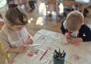 Dzieci kolorują mazakami swoje sylwety jajka wycięte zw sklejki.