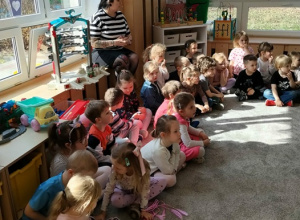 Dzieci siedzą na dywanie i słuchają.