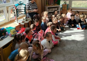 Dzieci siedzą na dywanie i słuchają Pani Agaty.