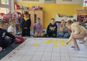 Dyktando graficzne z wykorzystaniem maty do kodowania. Dzieci układają kolorowe koła na macie wg kodu.