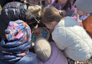 Dziewczynki liczą ile jajek znalazły w ogrodzie.