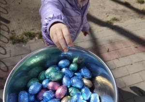 Dziewczynka wkłada do miski zebrane jajeczka.