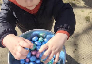 Chłopiec wkłada do miski skarby zajączka.