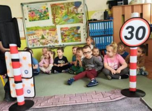 Dzieci siedzą na dywanie, Słuchają wypowiedzi przedstawicieli Łódzkiej Straży Miejskiej.