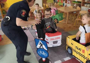 Przedstawiciel Straży Miejskiej zmienia kolor na sygnalizatorze- zatrzymuje ruch pojazdów.