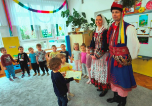 Dzieci wręczają gościom pamiątkowy dyplom w podziękowaniu za spotkanie.