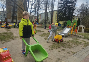 Chłopcy w ogrodzie przedszkolnym bawią się plastikowymi zabawkami.
