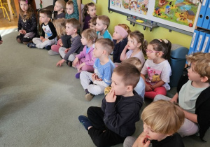 Dzieci siedzą na dywanie i słuchają