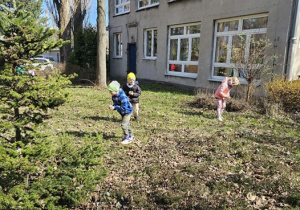 Dzieci biegają po ogrodzie i szukają wielkanocnych jajeczek