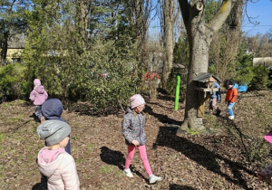 Dzieci biegają po ogrodzie i szukają wielkanocnych jajeczek
