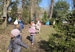 Dzieci biegają po ogrodzie i szukają wielkanocnych jajeczek