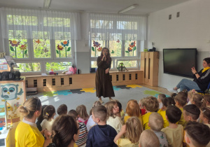 Dzieci siedzą na widowni i słuchają głosu operowego.