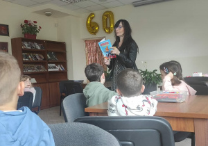 Pani bibliotekarka czyta dzieciom opowiadanie "Cudaczek Wyśmiewaczek.