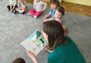 Pani Karolina czyta dzieciom bajkę o kotku.