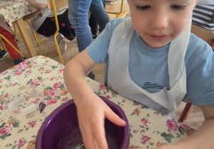 Chłopiec dosypuje ozdób do swojej miseczki ze slime'm