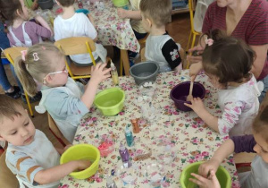 Dzieci mieszają masę z koralikami, cekinami i brokatem.