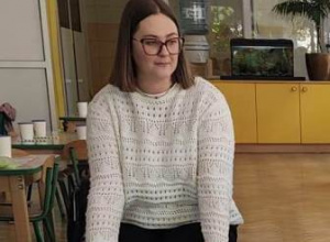 Mama kolegi siedzi na dywanie przed dziećmi i zaprasza do wspólnej zabawy.