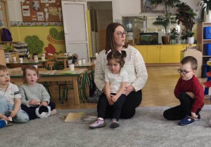 Pani Ola zaprasza dzieci do zabawy. Pokazuje dzieciom jak zrobić "buziaczki-śmieszaczki".