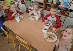 Dzieci z radością jedzą wykonaną przez siebie sałatkę owocową