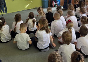 Starsze dzieci oglądają film edukacyjny o Świętach Majowych.