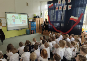 Młodsze dzieci oglądają bajkę edukacyjną o Polsce.