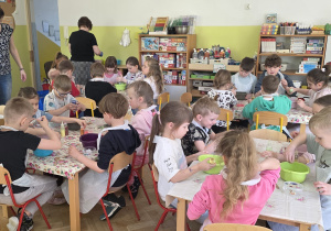 Dzieci ugniatają slajmy i dodają do nich ozdobne składniki, np. brokaty.