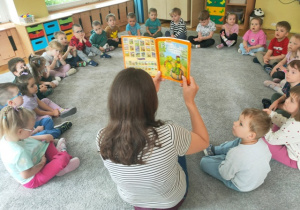 Mama pokazuje dzieciom ilustracje w książce.