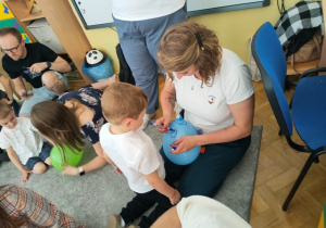 Mama dorysowuje na balonie oczy, ryjek i uśmiech śwince.