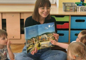 Mama pokazuje dzieciom ilustracje w książce.