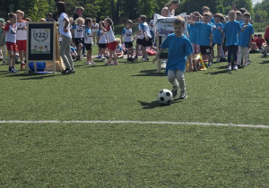 Chłopiec bierze udział w sportowych zmaganiach - kopie piłkę do wyznaczonego celu.