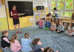 Dzieci słuchają książki czytanej przez Panią z Biblioteki Pedagogicznej w Łodzi.