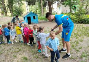 Trener stempluje dzieciom przedramię pieczątką okolicznościową,
