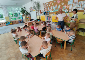 Dzieci siedzą w klasie przy stolikach i jedzą pyszne lody.