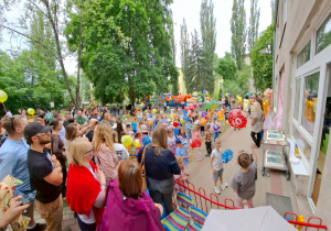 Dzieci, rodzice, pracownicy oraz przyjaciele naszego przedszkola bawią się wspólnie na pikniku rodzinnym.