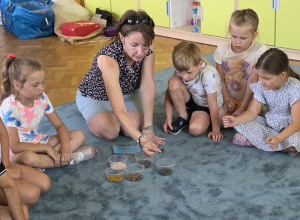 Dzieci siedzą na dywanie i rozmawiają z Panią prowadzącą warsztaty.