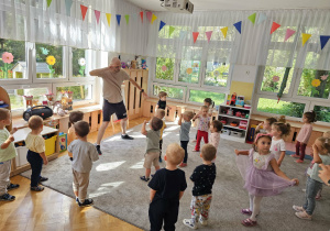 Dzieci tańczą wspólnie z Panem Darkiem podczas zajęć rytmiczno-tanecznych.