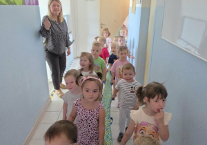 Dzieci idą korytarzem przedszkola i poznają jego zakamarki.