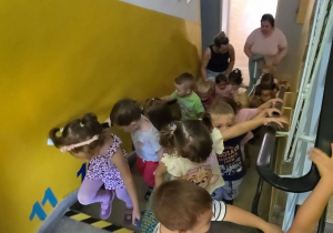 Dzieci wchodzą pod schodach, aby zobaczyć, co znajduje się na piętrze przedszkola.