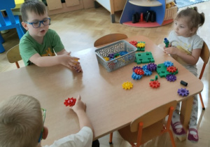Dzieci bawią się klockami konstrukcyjnymi przy stoliku.