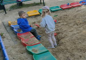 Dzieci bawią się w piaskownicy.