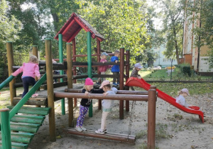 Dzieci bawią się na drewnianym sprzęcie ogrodowym.