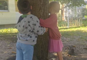 Dzieci obejmują lipę.