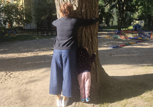 Ciocia wraz z dzieckiem z grupy tuli się do wierzby.