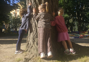 Dzieci przytulają się do wierzby.