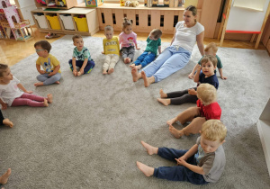 Dzieci siedzą na dywanie z gołymi stópkami.