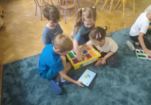Dzieci składają robota z lego według instrukcji z tabletu.