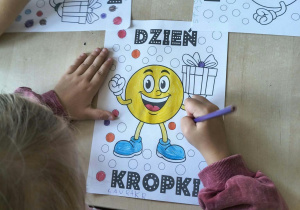 Dziewczynka koloruje kolorowankę związaną z Dniem Kropki.